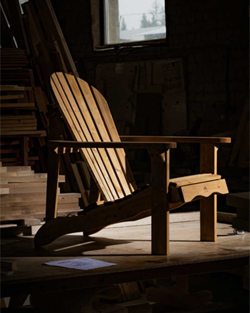 A brown wooden Adirondack chair in a workshop