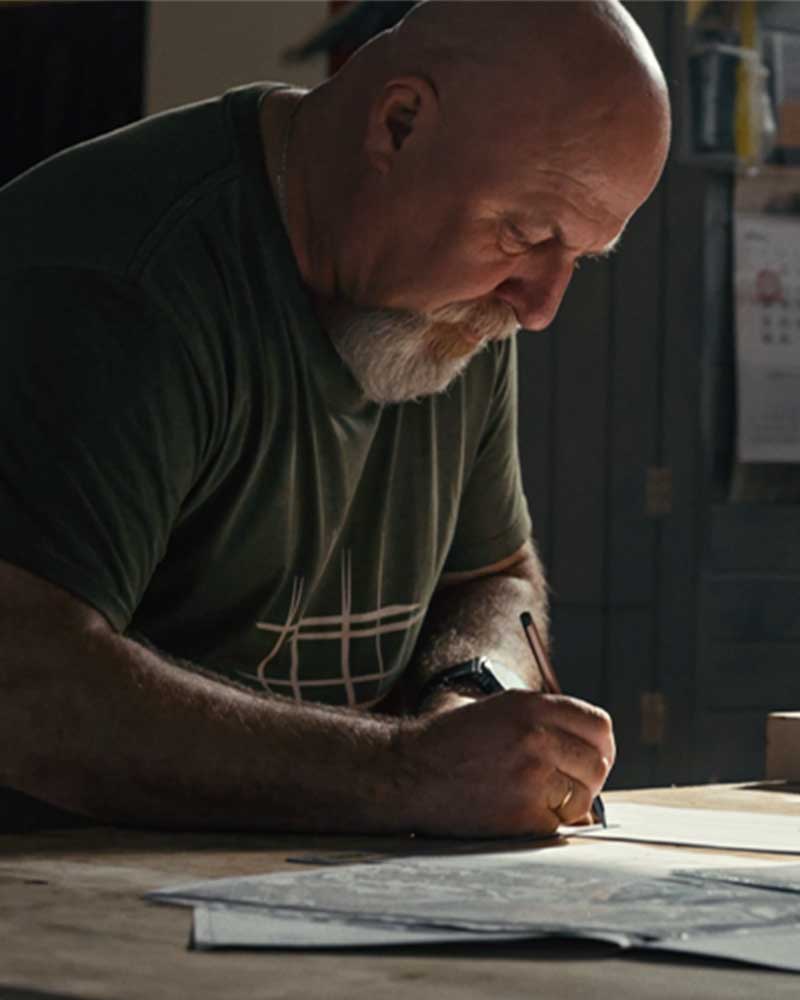 A man with a beard drawing up wood furniture design pattern