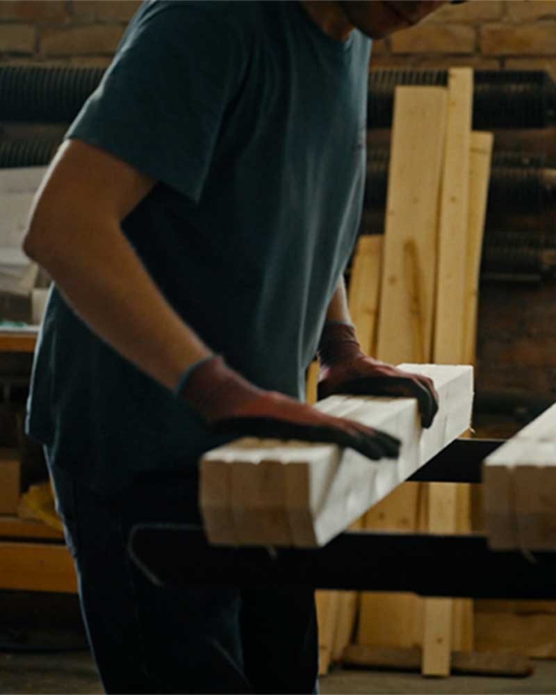 Man stacking wood planks in a workshop