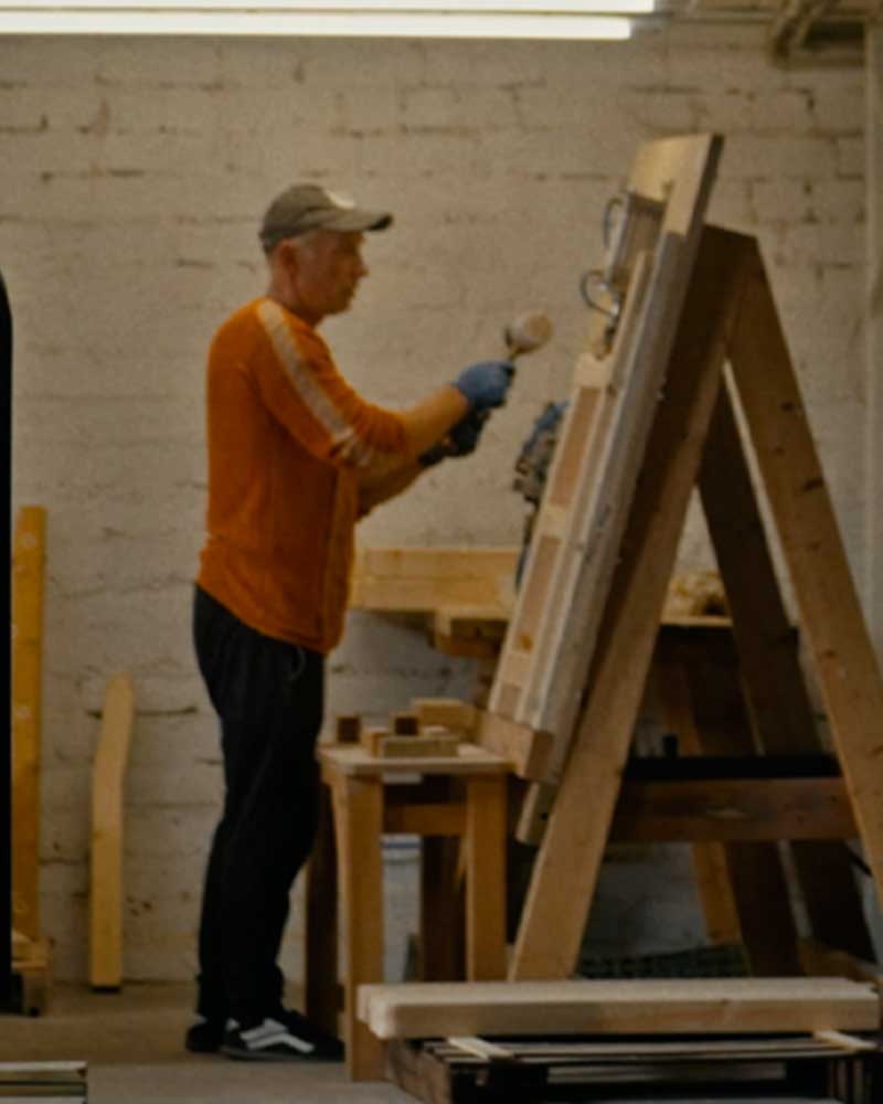 Man painting wood samples in a workshop