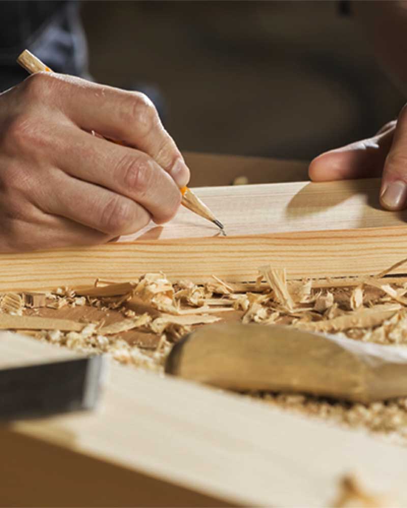 A closeup of a man drawing on wood