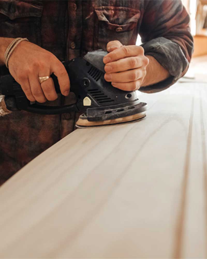 A closeup of a man sanding wood